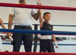 a youth boxer with confidence in a tucson gym. The fer his holding the boxing champions hand in the air